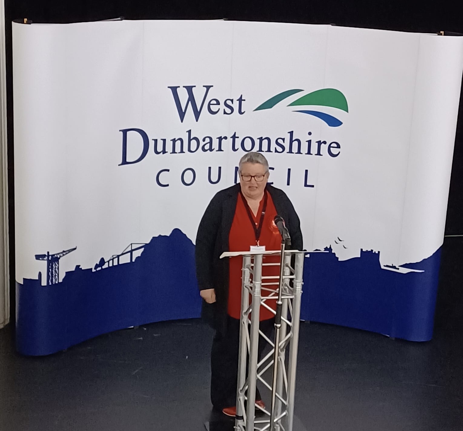 Woman standing on stage in front of West Dunbartonshire Council logo